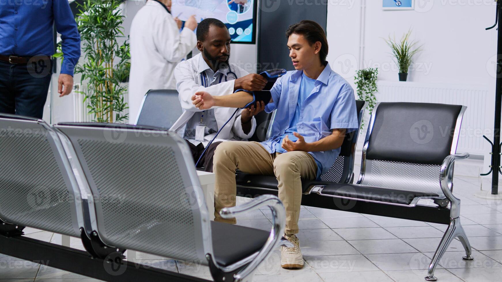 Cardiologist using medical tonometer to measure patient pulse pressure and hypertension, doing cardiology exam and cardiac test in hospital reception. Medic and young adult attending checkup visit. photo