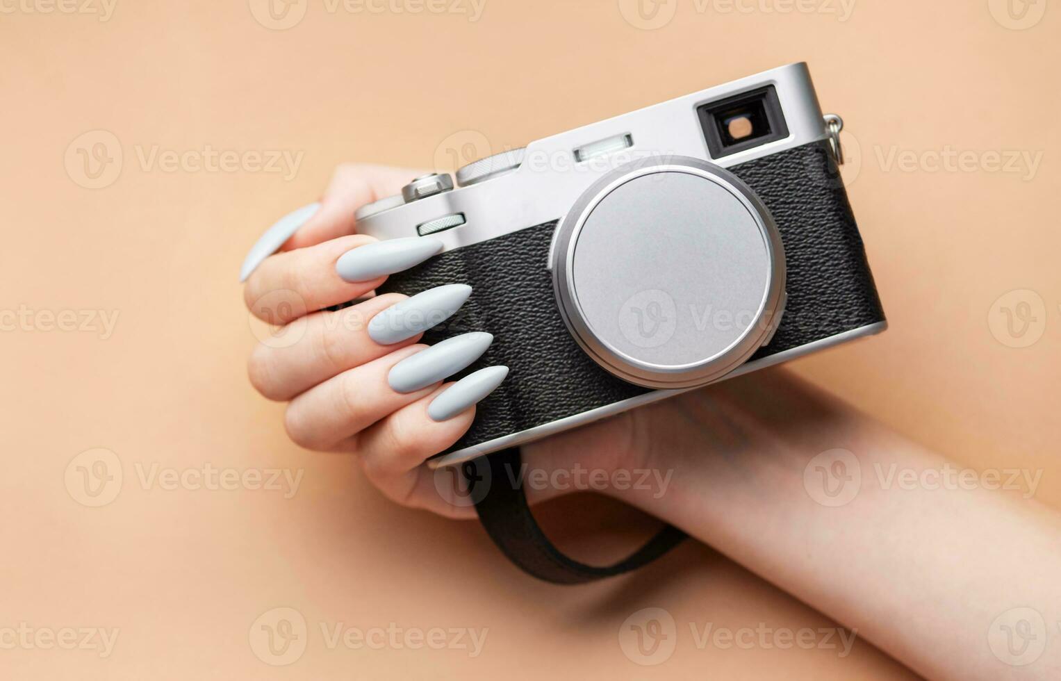 Woman's hand with grey nail polish holding camera photo