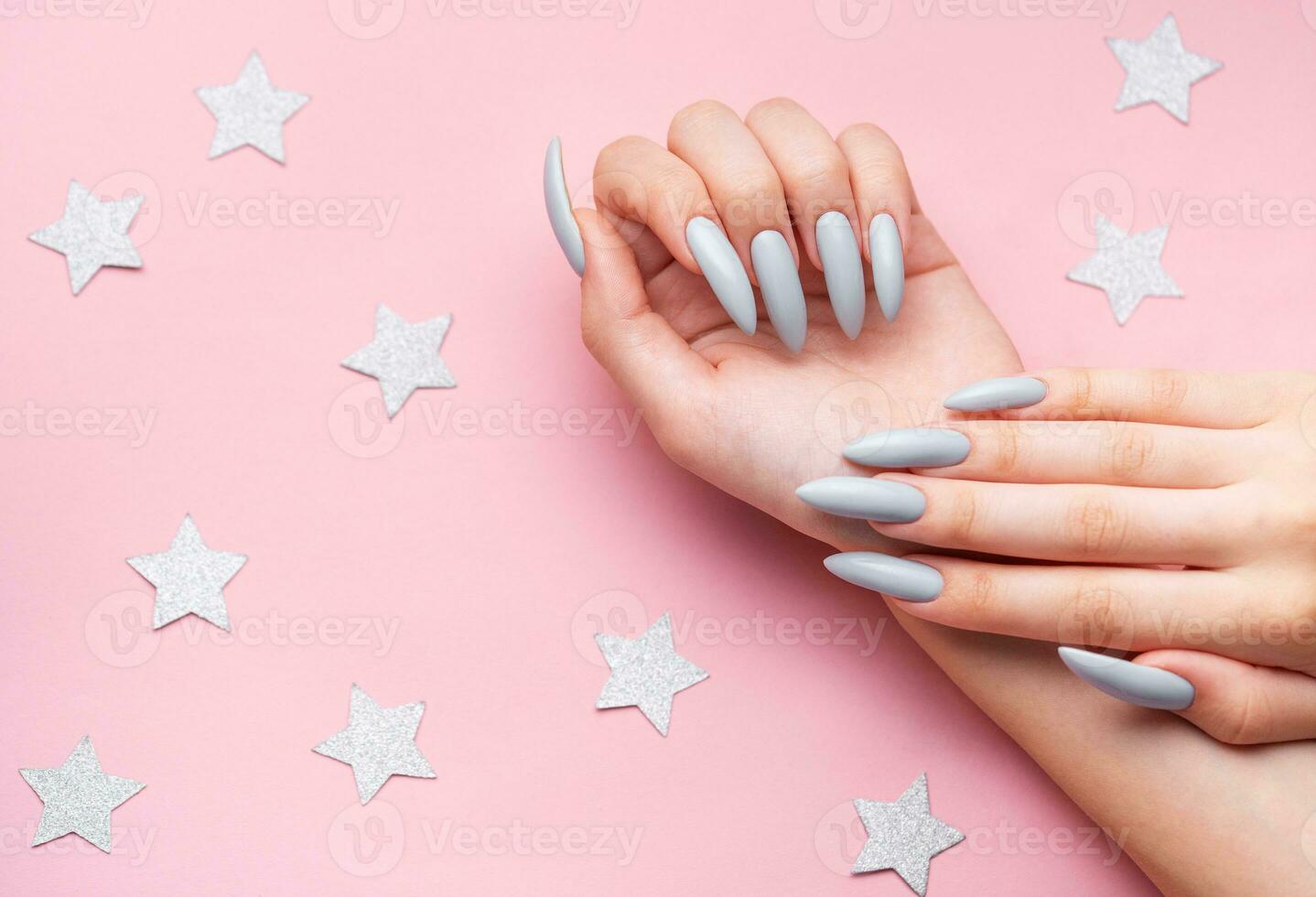 Hands with grey manicure on a pink background photo