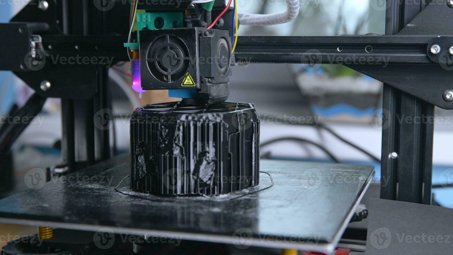 A 3D printer prints a black model. Technology at home photo