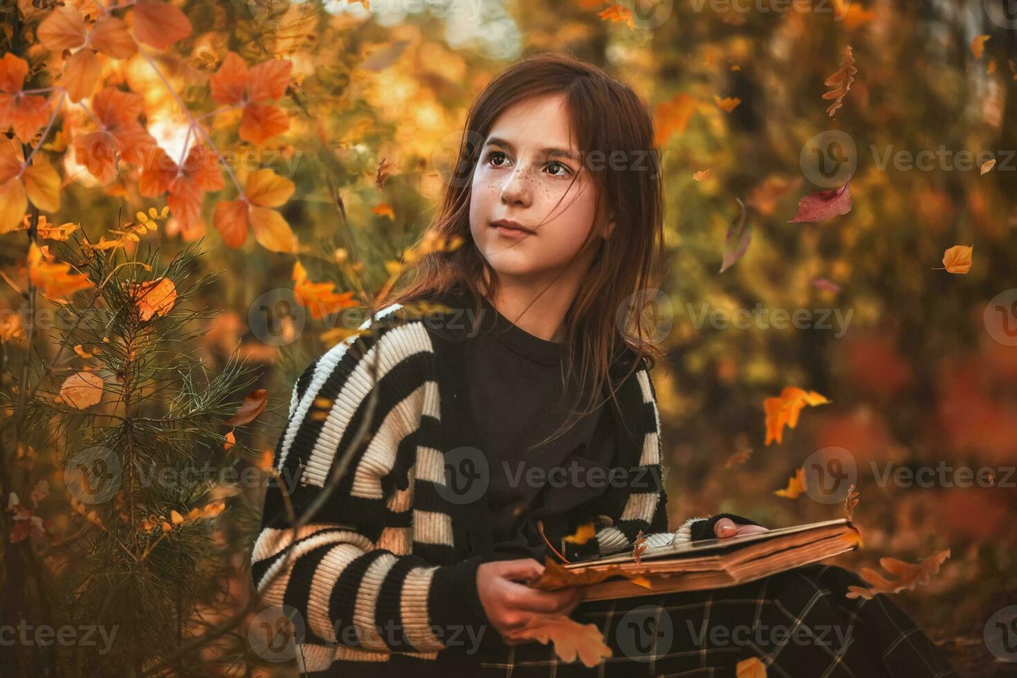 niña con pecas con un libro entre otoño hojas foto