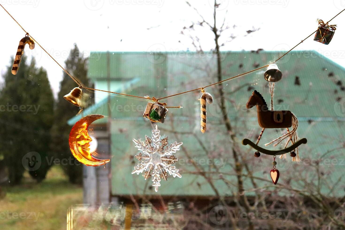 Christmas window overlooking the courtyard in a rural house with a garland of Christmas tree toys of a horse, a moon, a sugar cane, snowflakes, horizontal photo