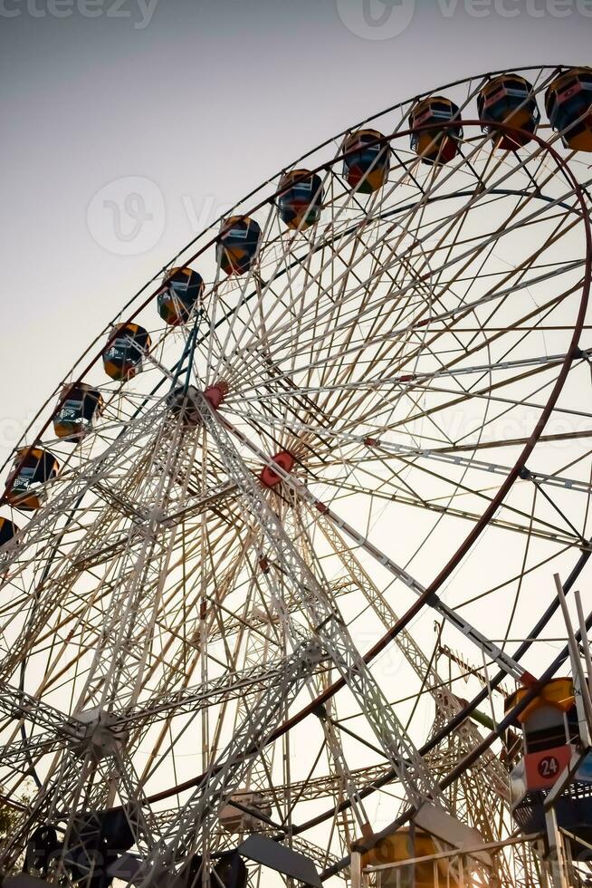 Closeup of multi-coloured Giant Wheel during Dussehra Mela in Delhi, India. Bottom view of Giant Wheel swing. Ferriswheel with colourful cabins during day time. photo