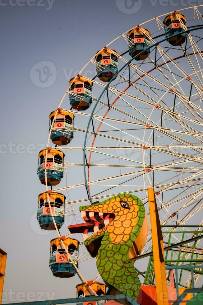 Closeup of multi-coloured Giant Wheel during Dussehra Mela in Delhi, India. Bottom view of Giant Wheel swing. Ferriswheel with colourful cabins during day time. photo