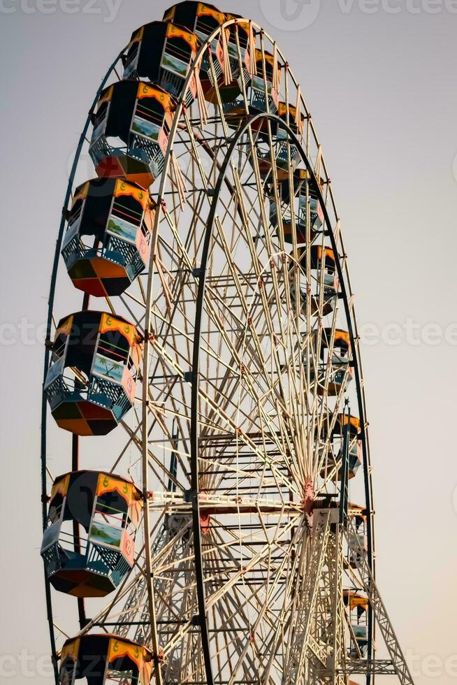 Closeup of multi-coloured Giant Wheel during Dussehra Mela in Delhi, India. Bottom view of Giant Wheel swing. Ferriswheel with colourful cabins during day time. photo