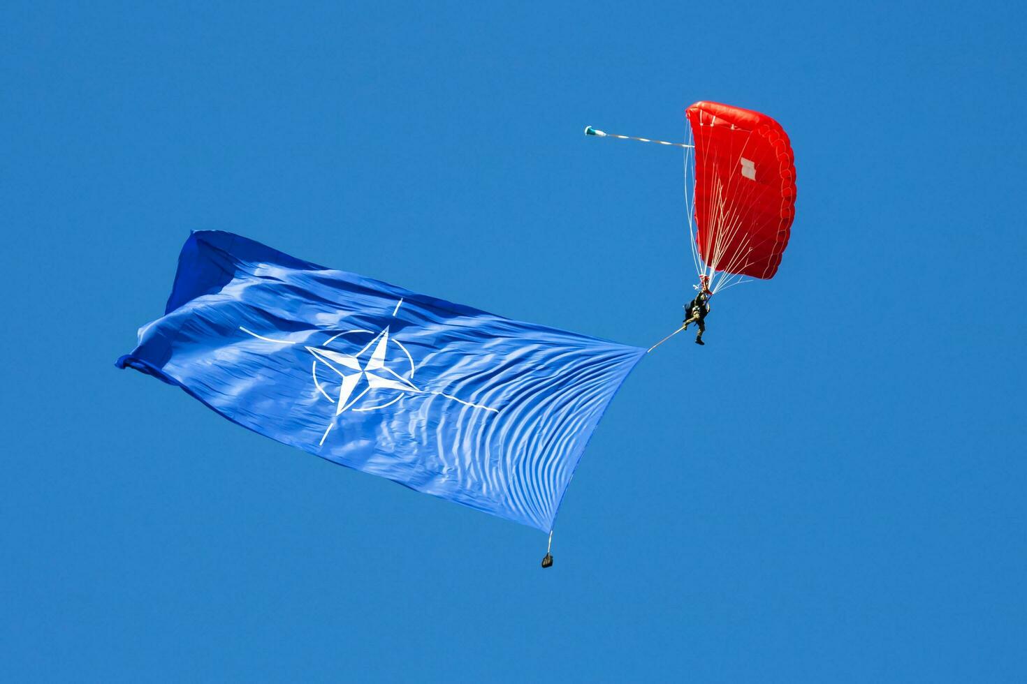 Paratrooper flying in the sky. Extreme sport and Xgames. Jumping with NATO flag. photo