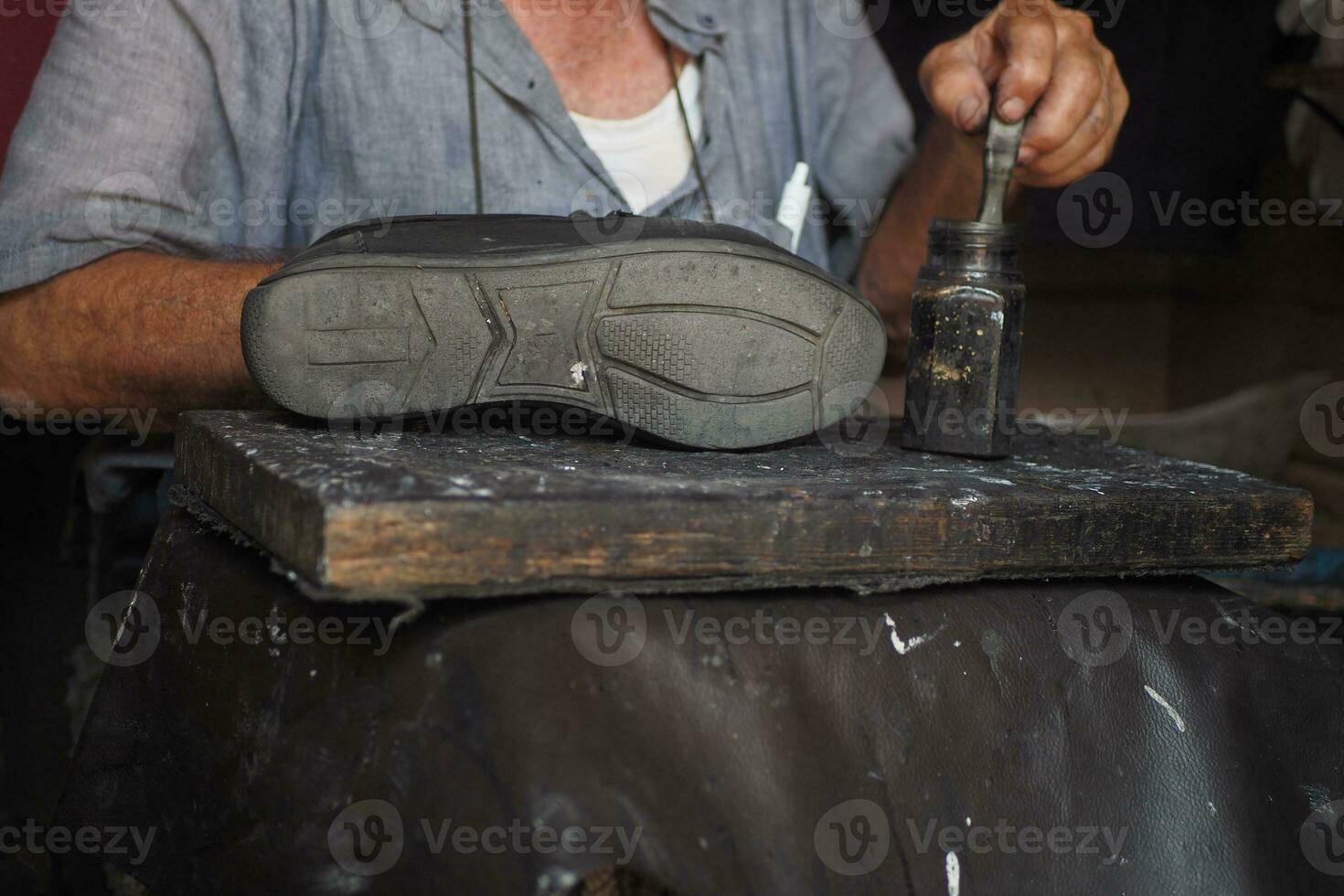 A cobbler's hands mending shoe stitching with needle photo