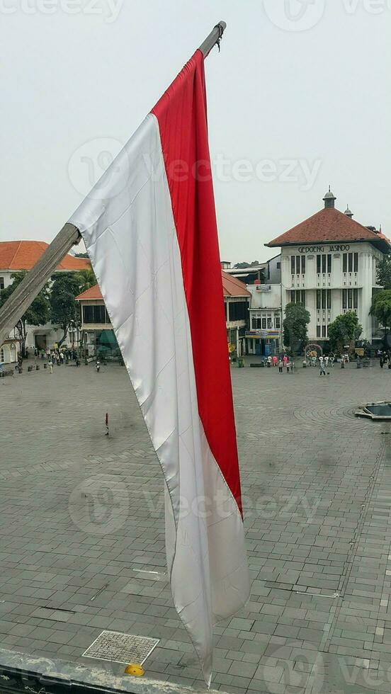 el indonesio rojo y blanco bandera revolotea en parte superior de el antiguo holandés patrimonio edificio. ver desde el ventana. foto