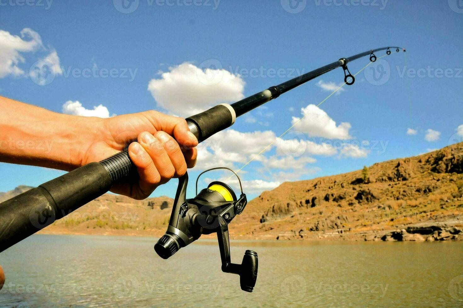 a person holding a fishing rod and reel photo
