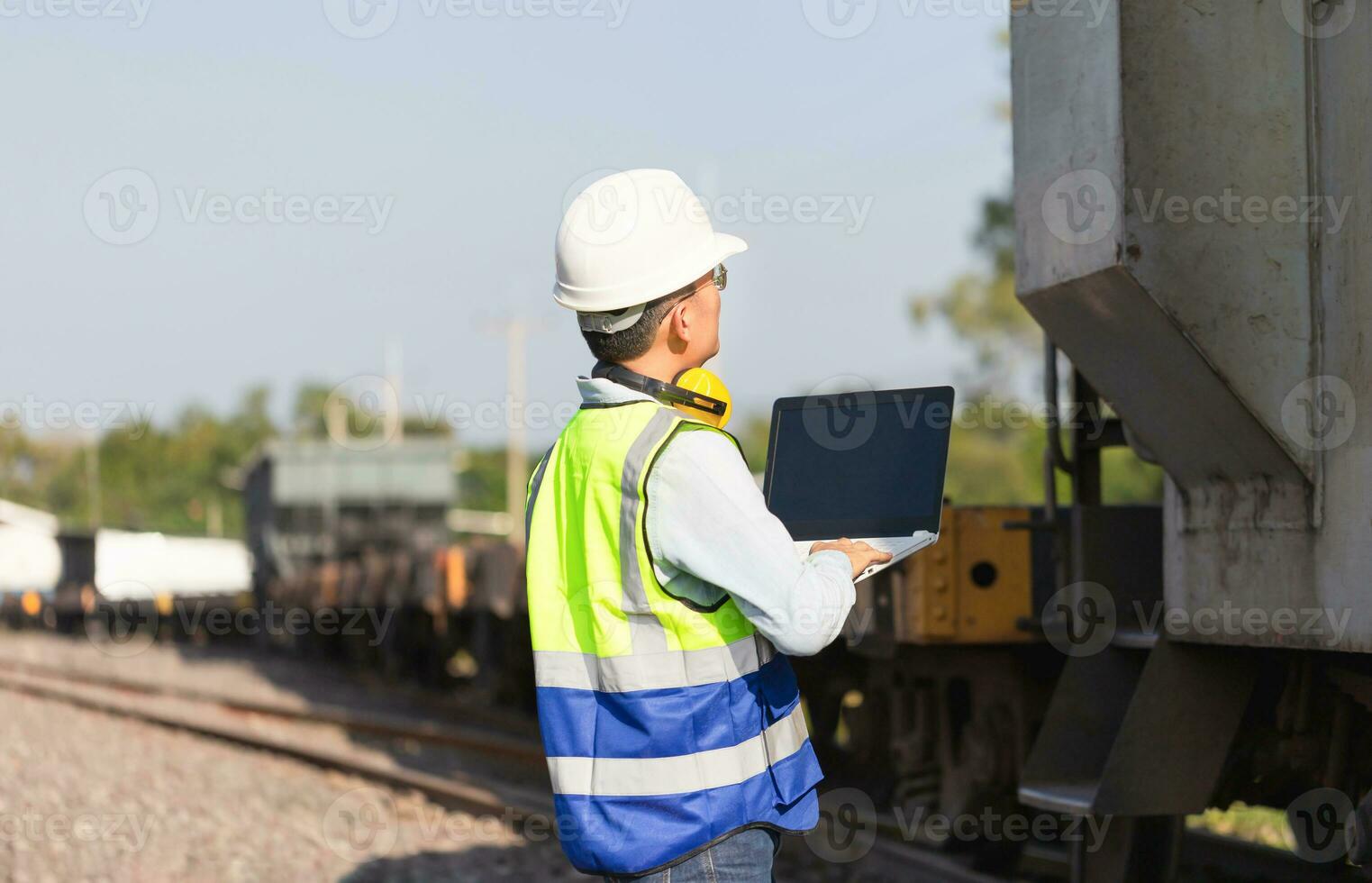 Engineer under inspection and checking construction process railway locomotive repair plant, Engineer man in waistcoats and hardhats and with laptop in a railway depot photo