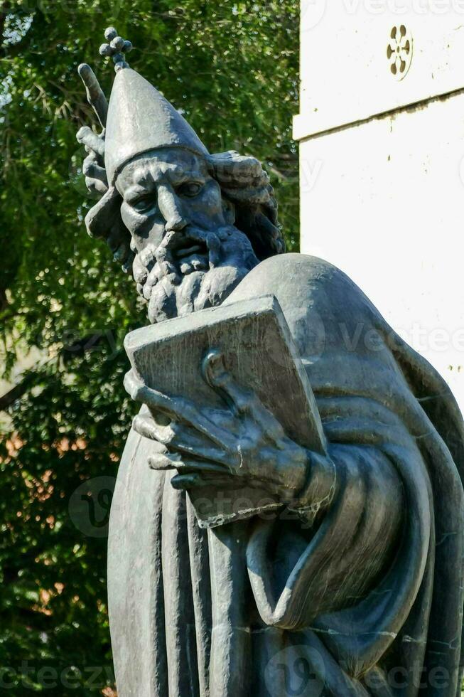 statue of a man holding a book in front of a building photo