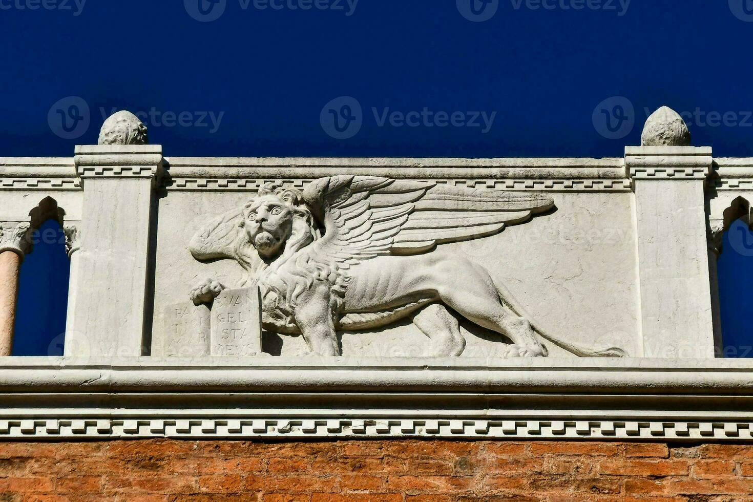 a statue of a griffin on a building against a blue sky photo