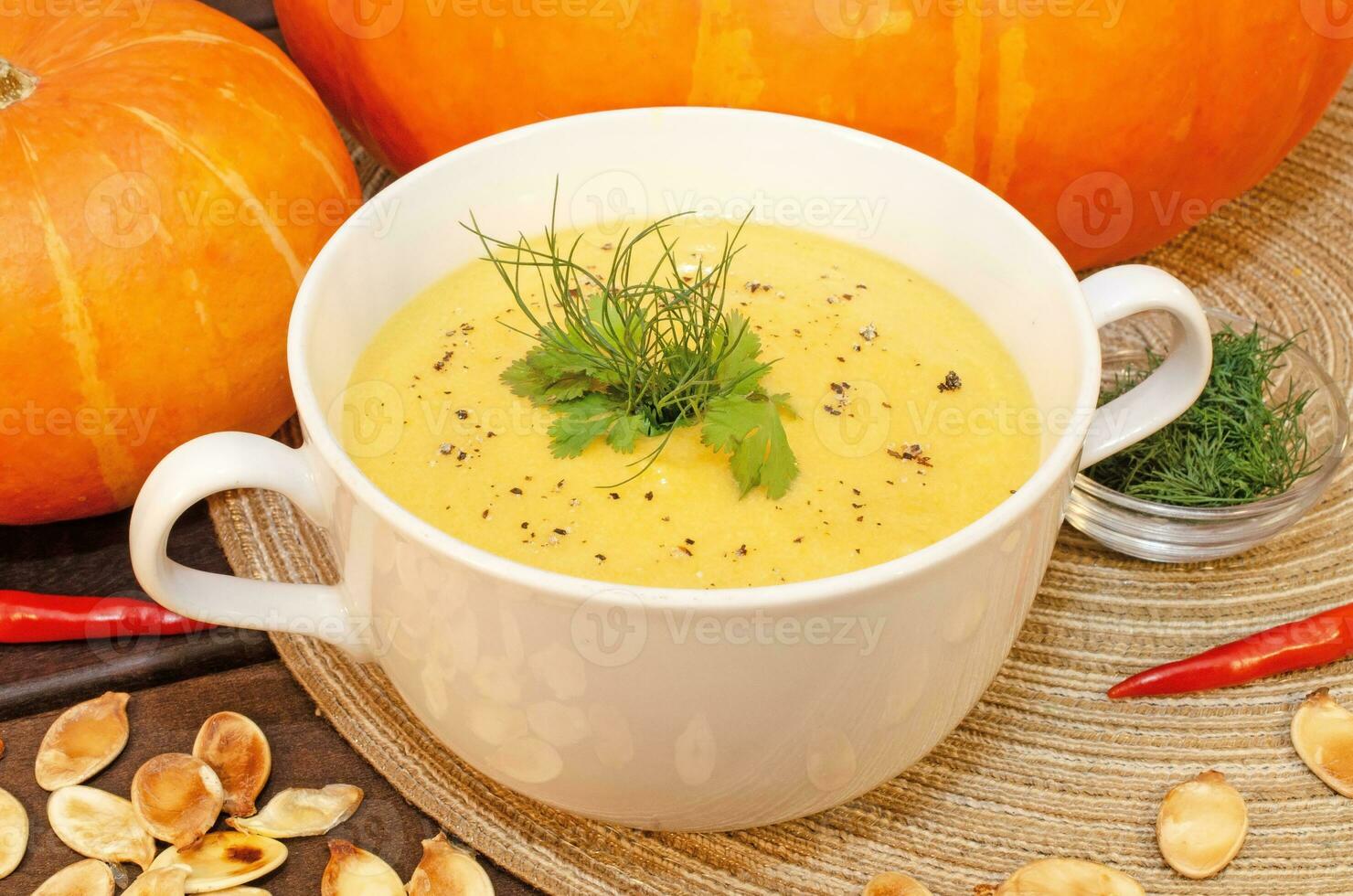 Pumpkin hot puree soup on a wooden table photo