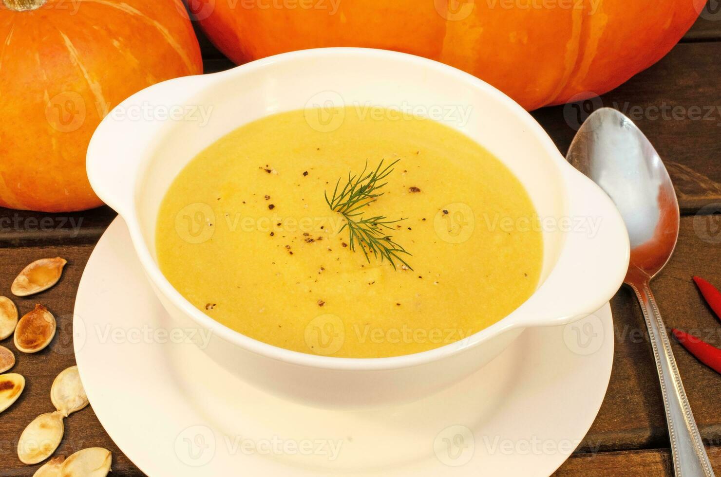 Pumpkin hot puree soup on a wooden table photo