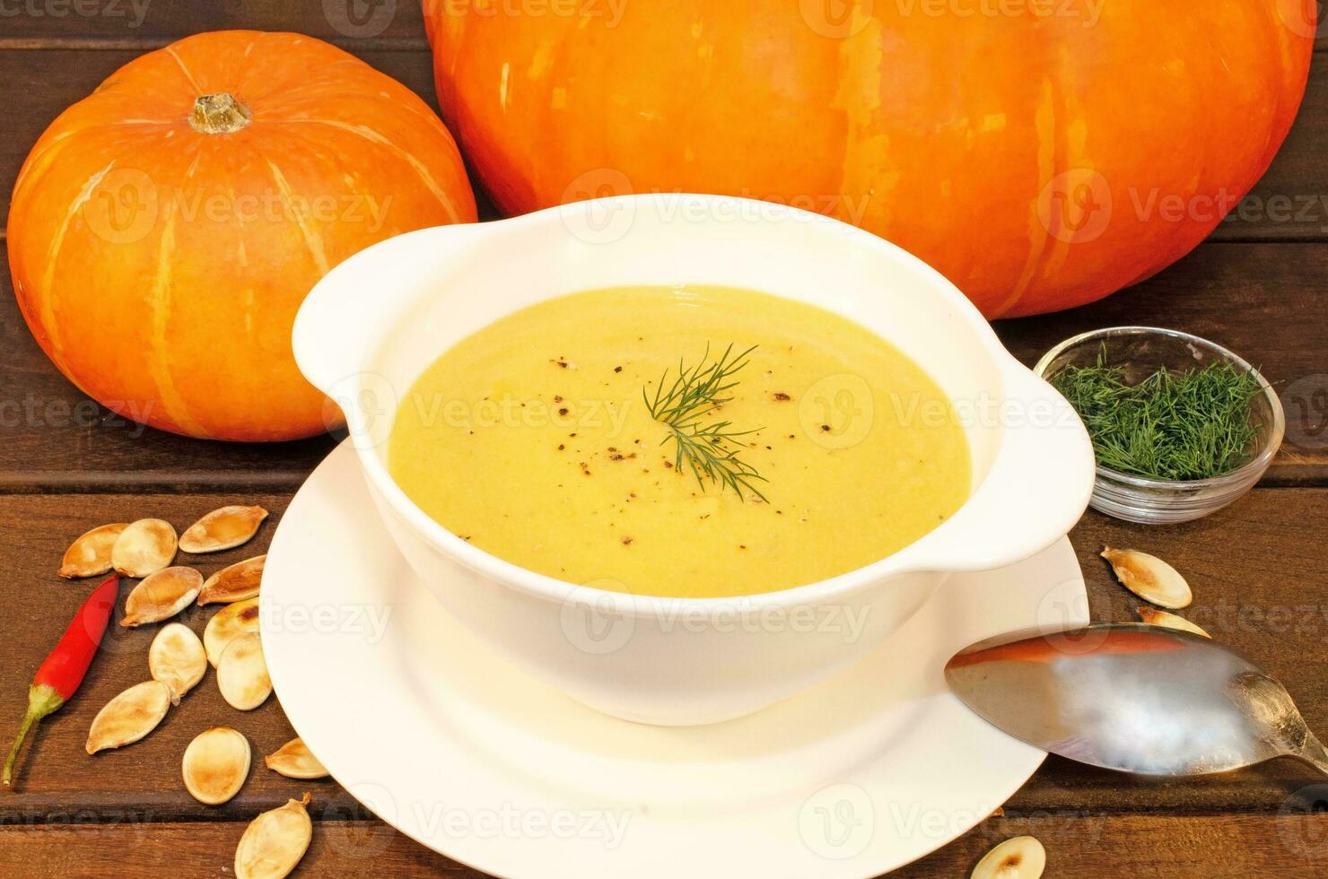 Pumpkin hot puree soup on a wooden table photo