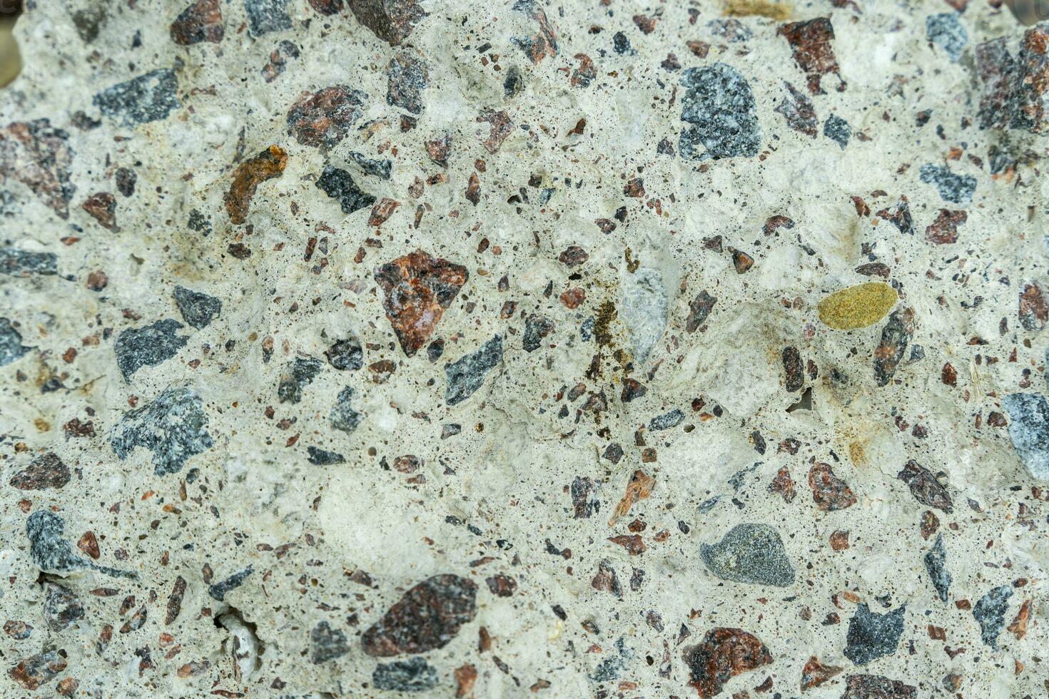 textured background of gray chipped concrete interspersed with stones photo