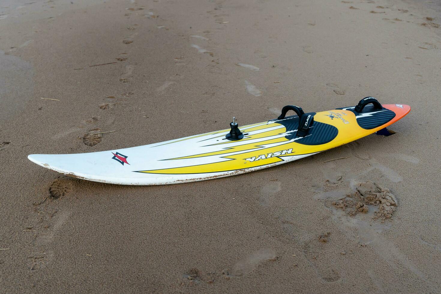 Sosnovy Bor, RUSSIA - OCTOBER 15, 2023 A surfboard lying on the sand of beach photo