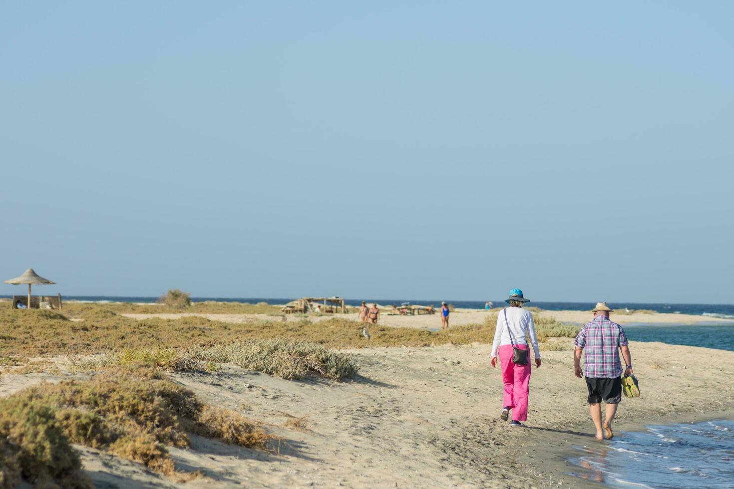 lot of people walking in the sand on the beach near the sea during vacation in the spring photo