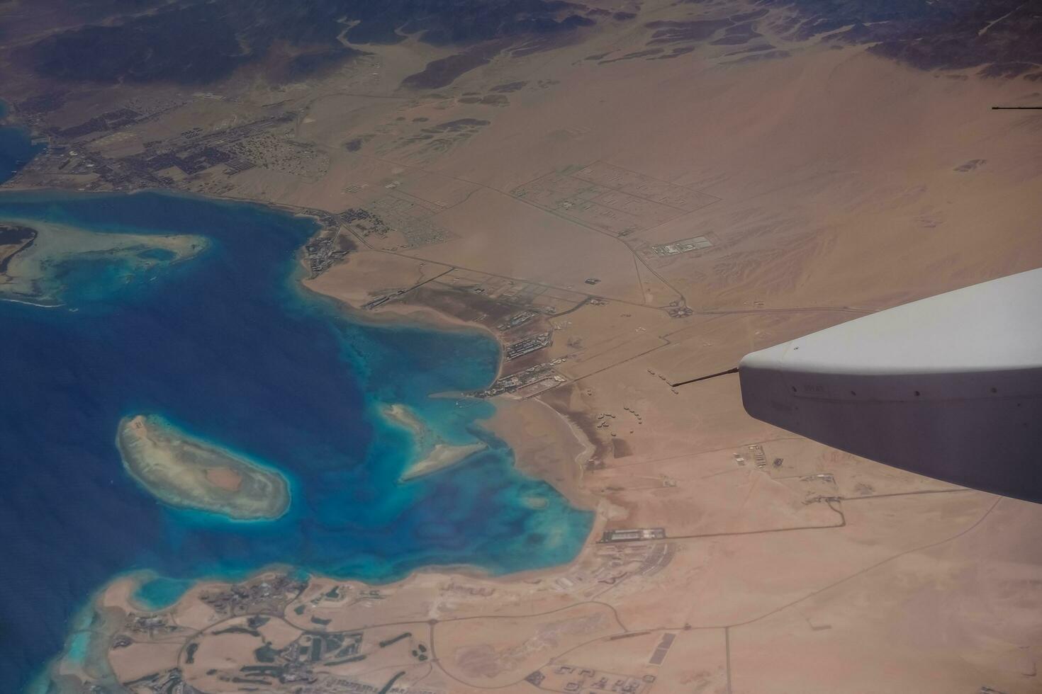 flight over a bay with coral reef and a desert with lot of roads photo