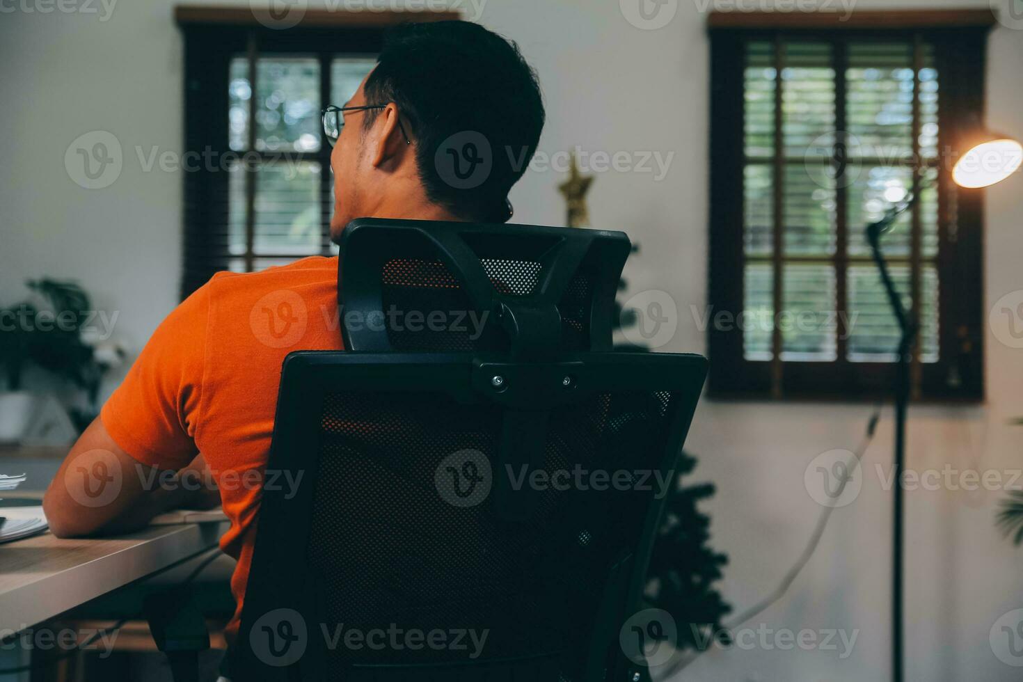 Satisfied caucasian successful guy, freelancer or ceo, relaxes at workplace with legs thrown on table. Stylish guy uses laptop, browses the Internet, looks for ideas for a project, sitting at the desk photo
