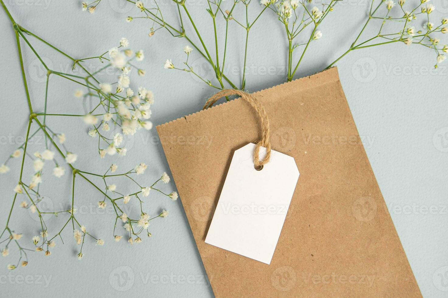 A mock-up of an empty tag, label and price tag near an eco-package with flowers lie on a gray table photo