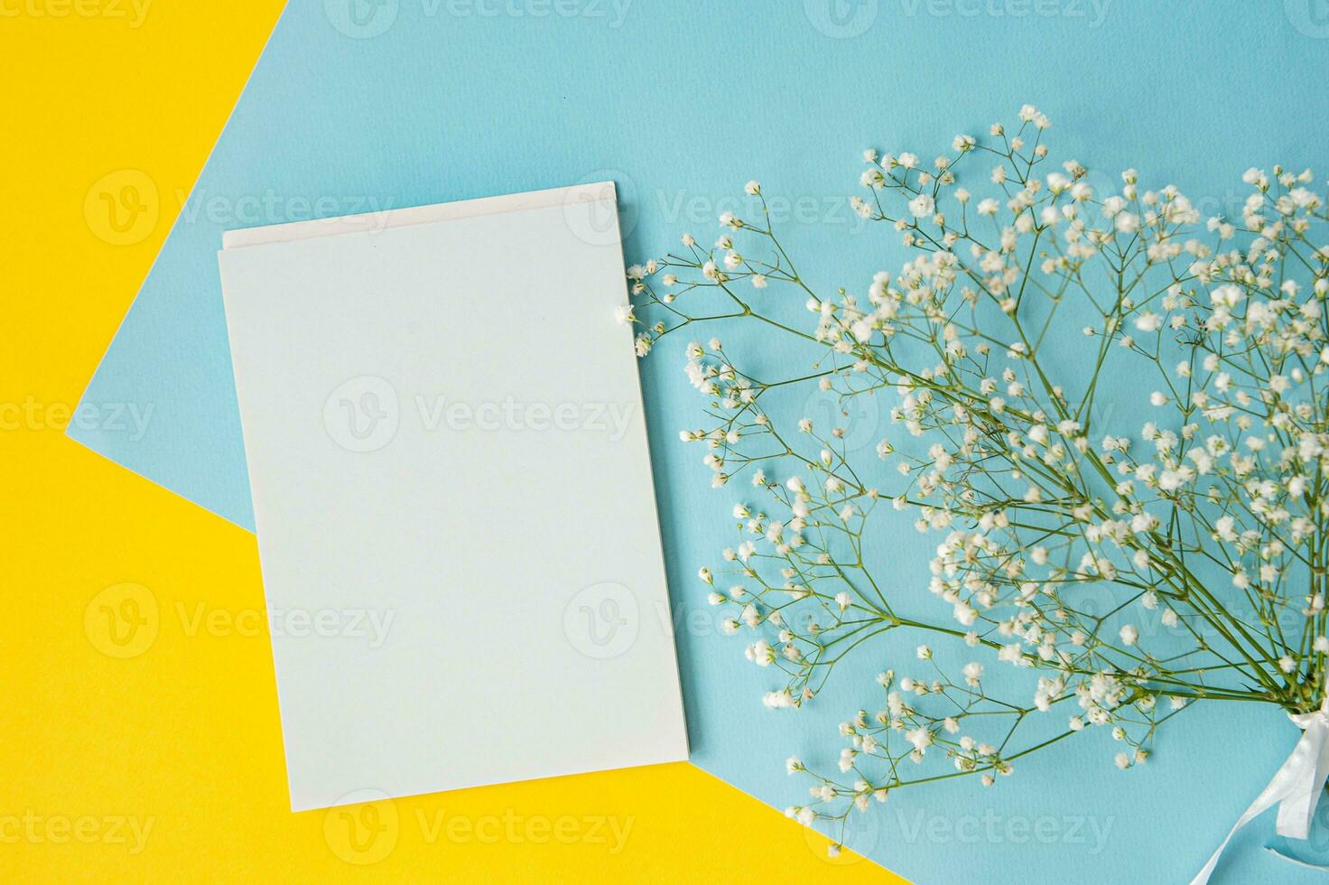 Mockup of a white notebook on a colored blue and yellow background with a bouquet of gypsophila photo