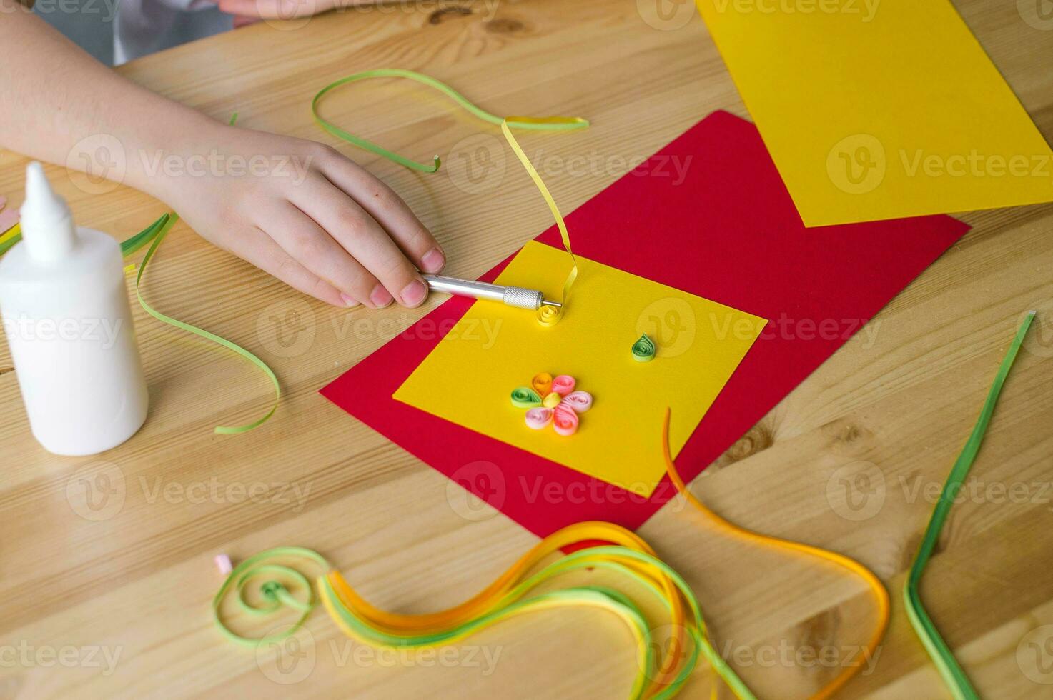 Making postcards from long and narrow strips of paper twisted into spirals, quilling photo