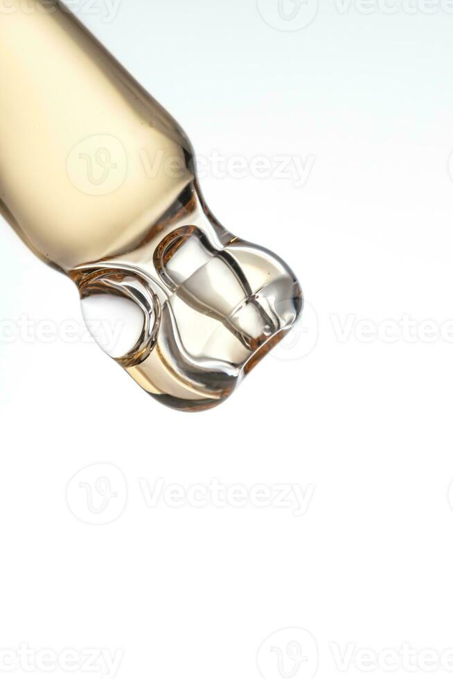 close up of pipette with pouring liquid serum and shadows on white background. Trendy cosmetics shot photo