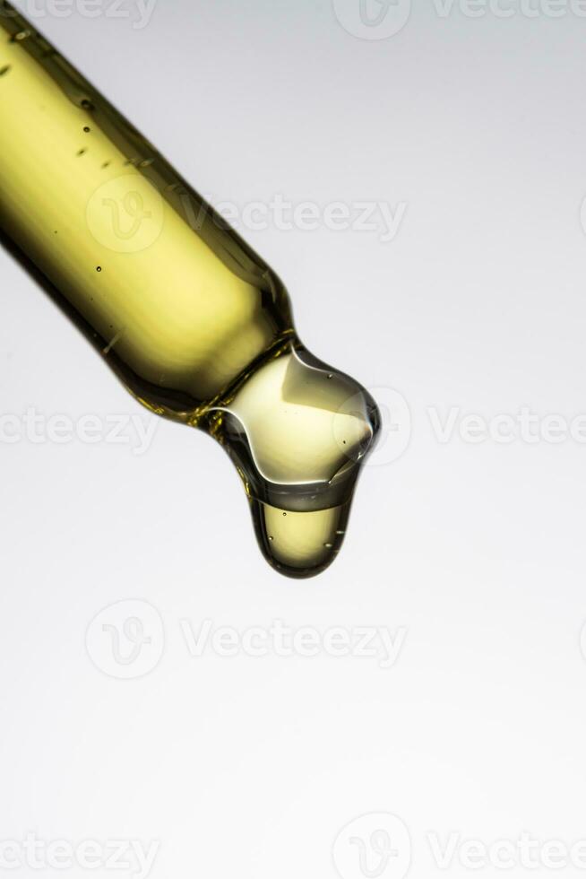 closeup of a serum pipette with a falling drop on a white background photo