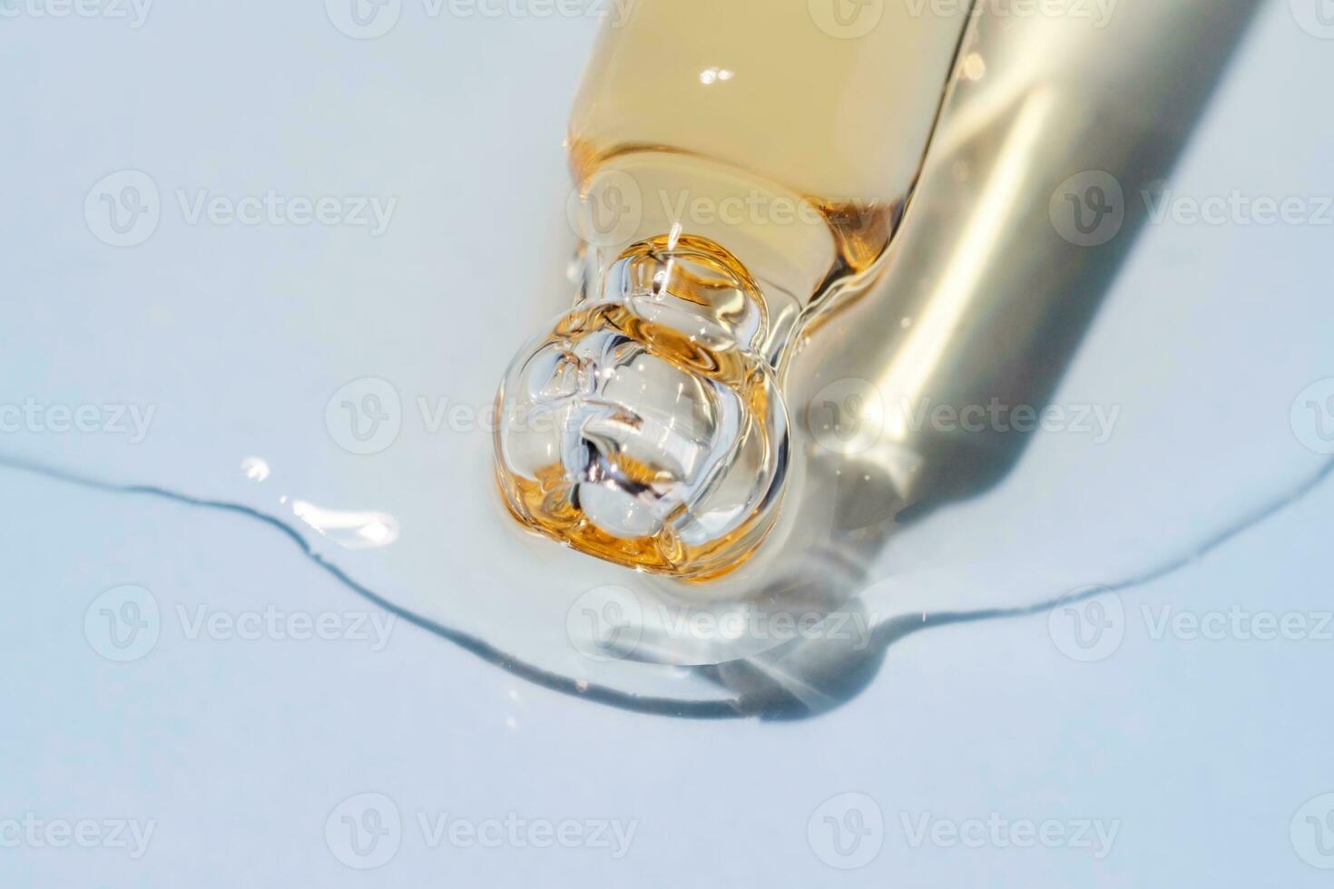 Bottle pipette dropper close up and Liquid yellow-orange retinol or vitamin c gel or serum on a blue background photo