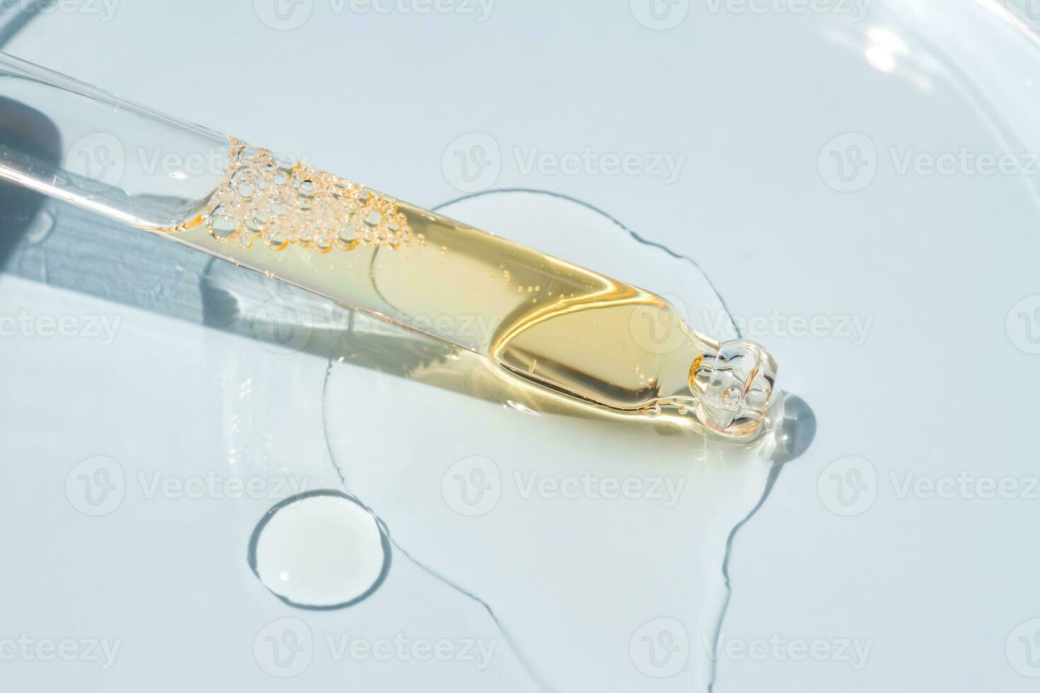 Bottle pipette dropper close up and Liquid yellow-orange retinol or vitamin c gel or serum on a blue background photo