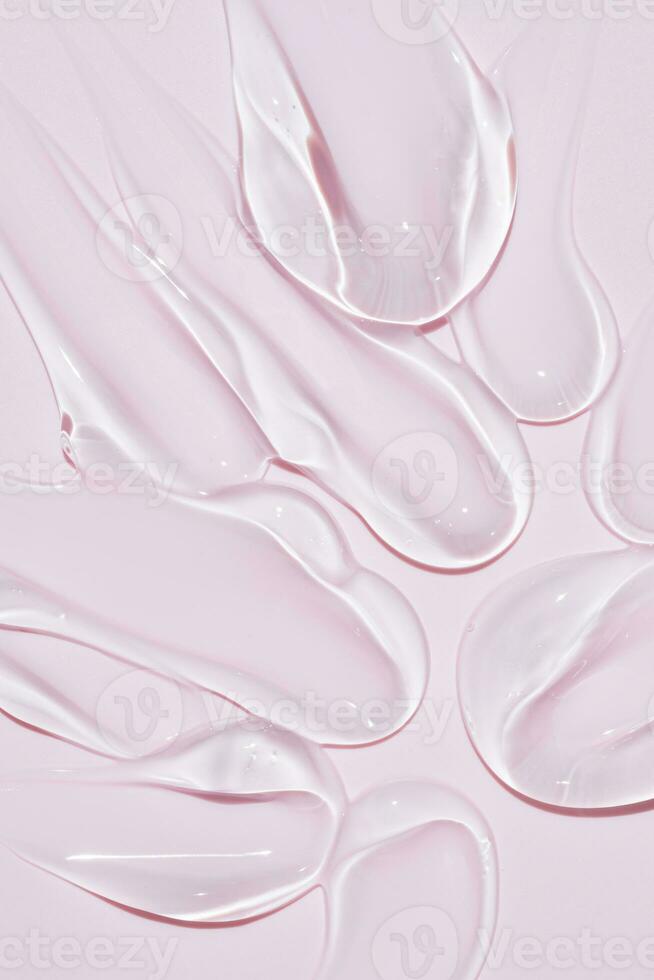 Liquid gel smear isolated on pink background. Beauty cosmetic smudge such as pure transparent aloe lotion, facial jelly serum, cleanser, shower gel or shampoo top view. photo