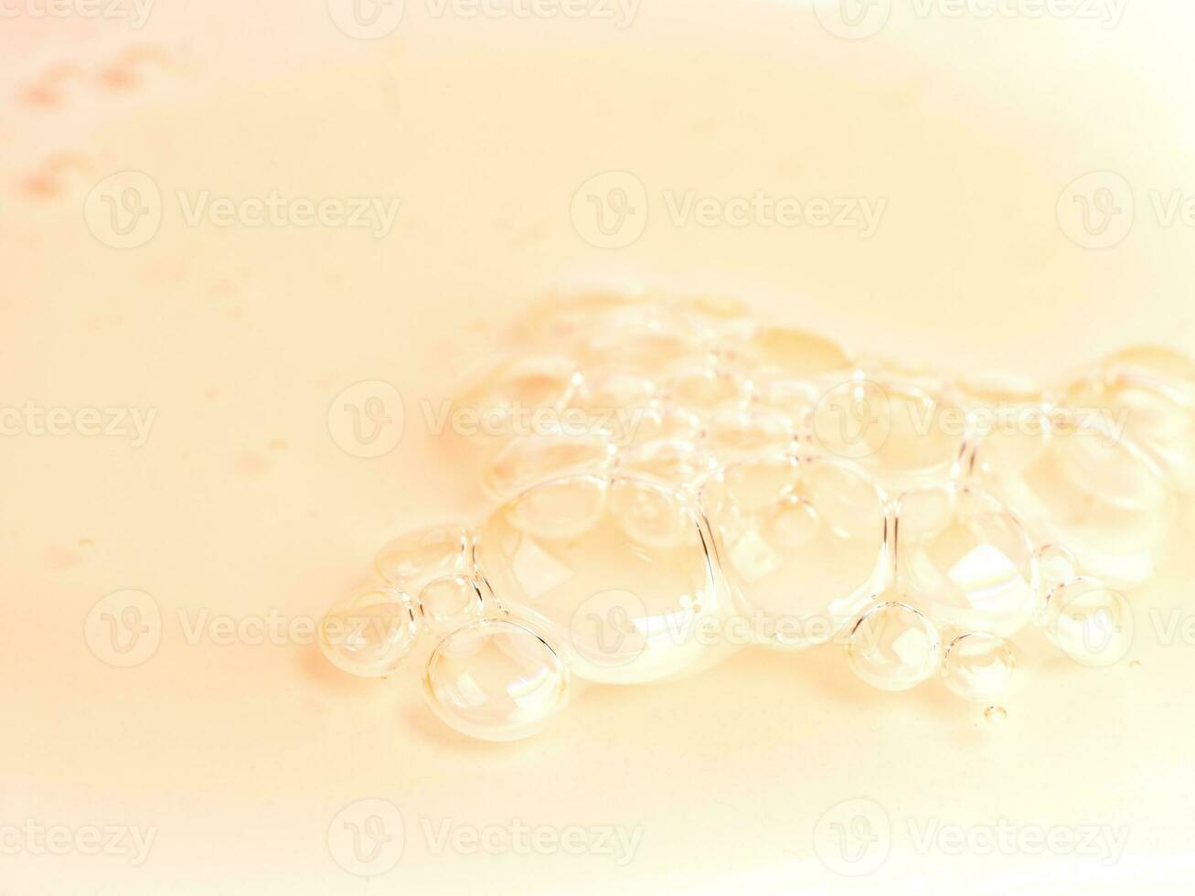 macro of orange liquid face cleansing gel or soap with bubbles. Close up of skin care product photo