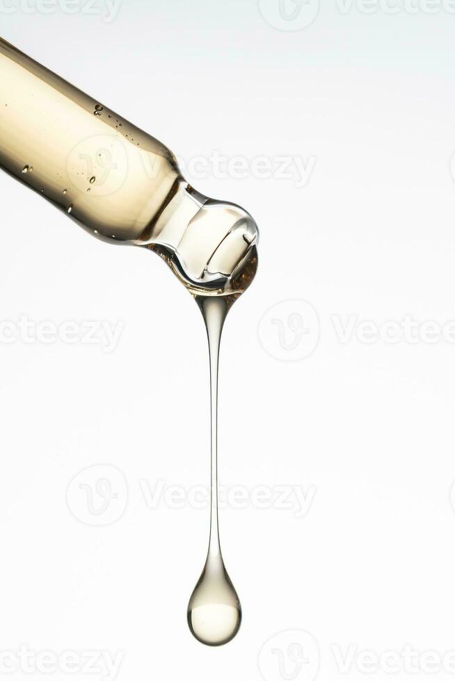 Pipette with serum, gel, oil or other cosmetic product with falling drop. Macro closeup photo