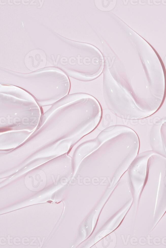 Liquid gel cosmetic smudge drops texture on bpink background. cosmetic smears cream texture. skin care product stroke flat lay, cream with hyaluronic acid photo