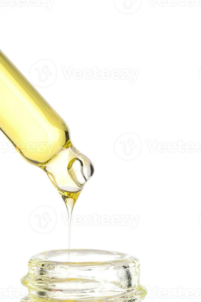 essential oil falling from glass dropper into a glass bottle. Cosmetic laboratory research photo