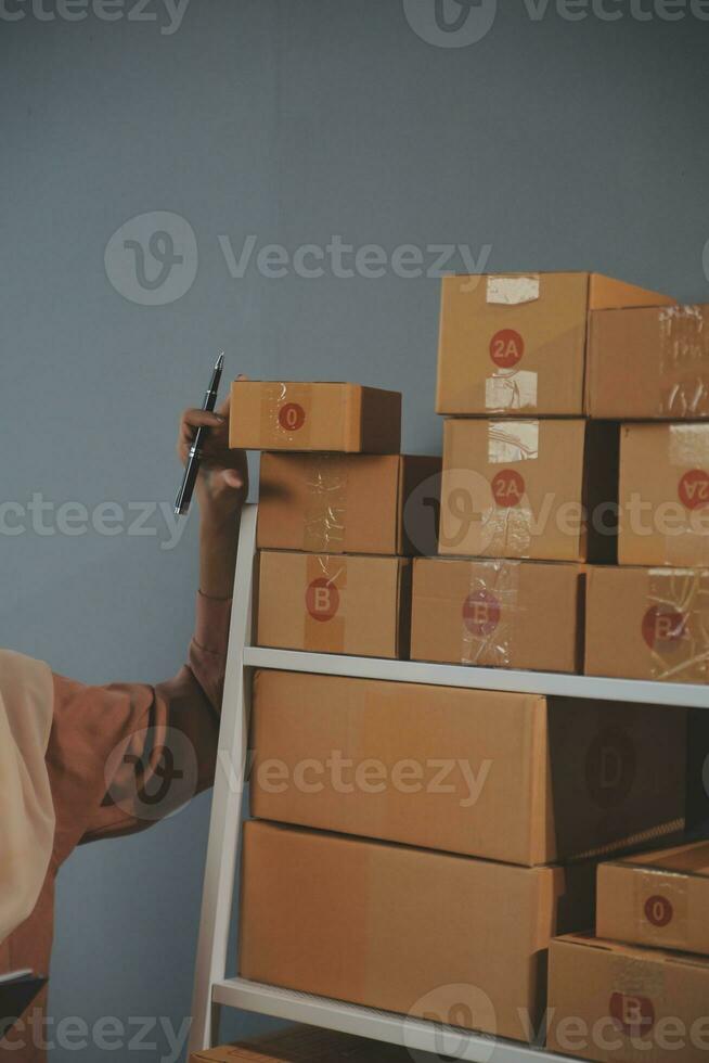 Starting small businesses SME owners female entrepreneurs Write the address on receipt box and check online orders to prepare to pack the boxes, sell to customers, sme business ideas online. photo