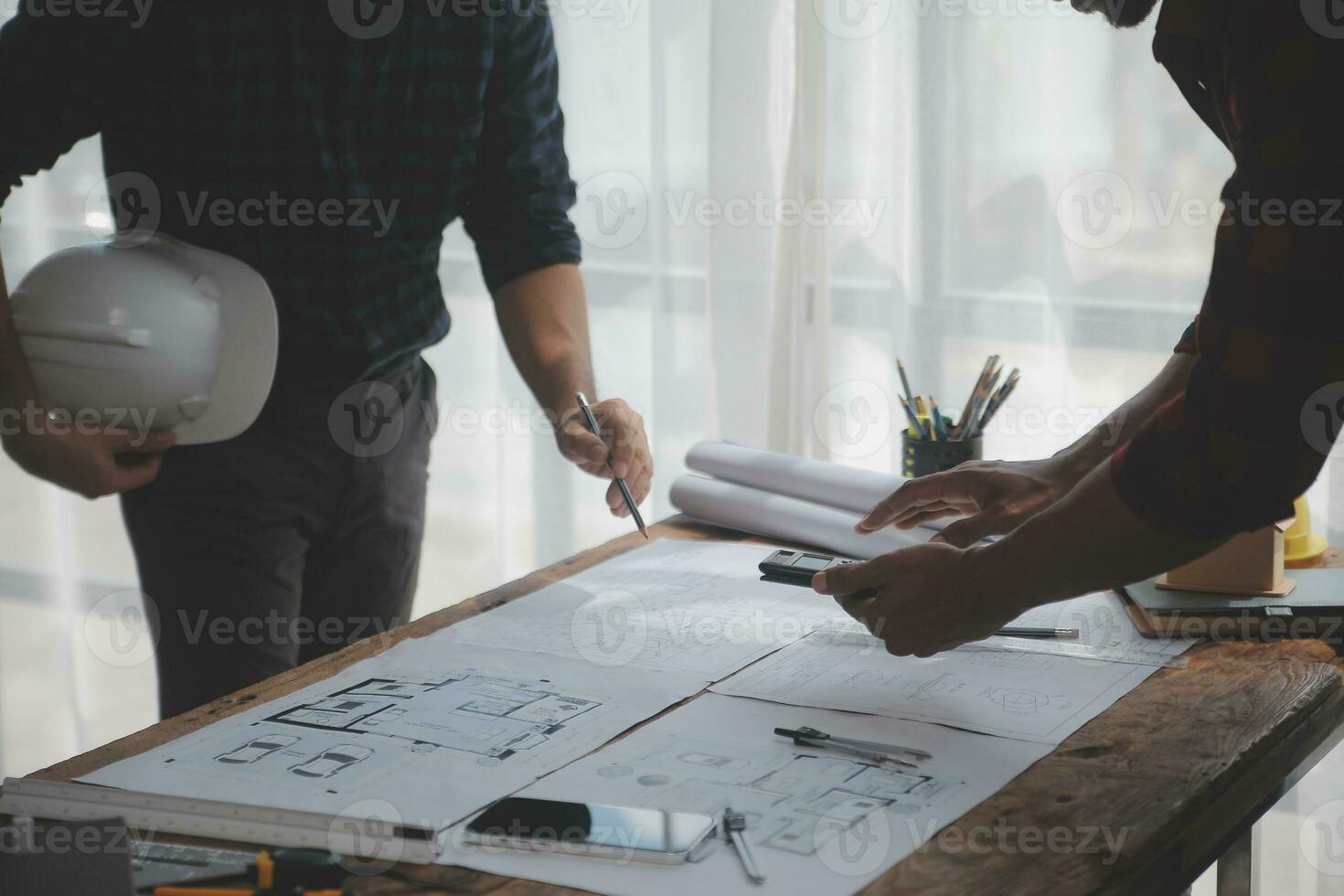 Close up of civil male engineer asian working on blueprint architectural project at construction site at desk in office. photo