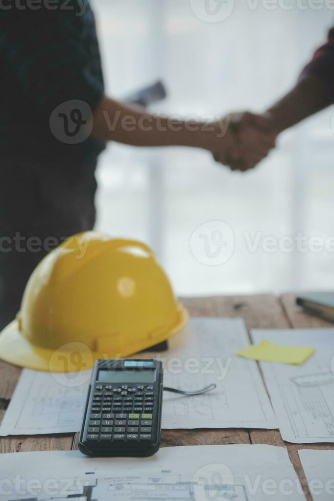 Close up of civil male engineer asian working on blueprint architectural project at construction site at desk in office. photo