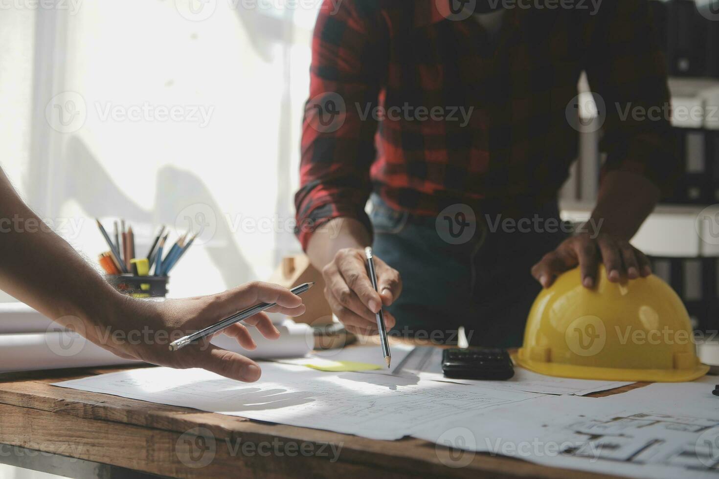 Close up of civil male engineer asian working on blueprint architectural project at construction site at desk in office. photo
