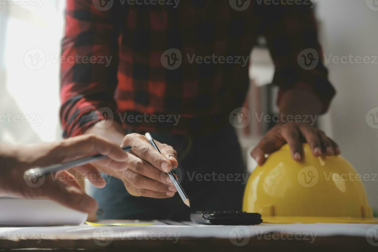 Close up of civil male engineer asian working on blueprint architectural project at construction site at desk in office. photo