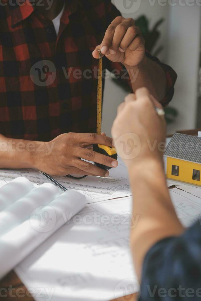 Close up of civil male engineer asian working on blueprint architectural project at construction site at desk in office. photo