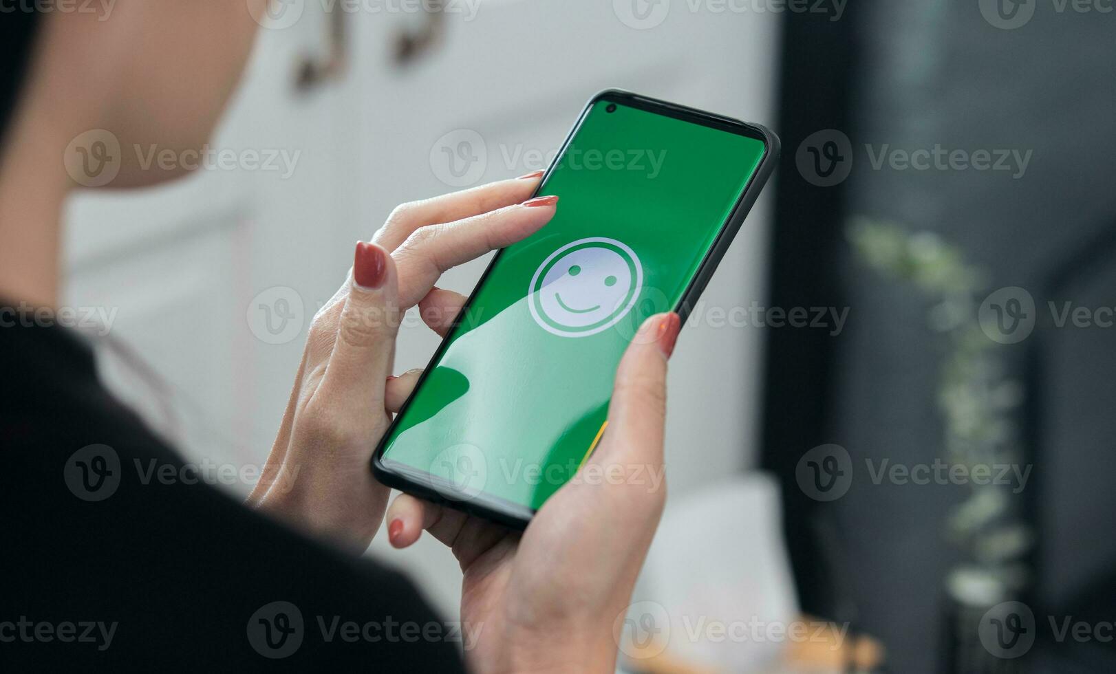 Woman holds a Smartphone with happy emoticons on the screen at a restaurant. concept of evaluating customer satisfaction at very good level of customer service photo