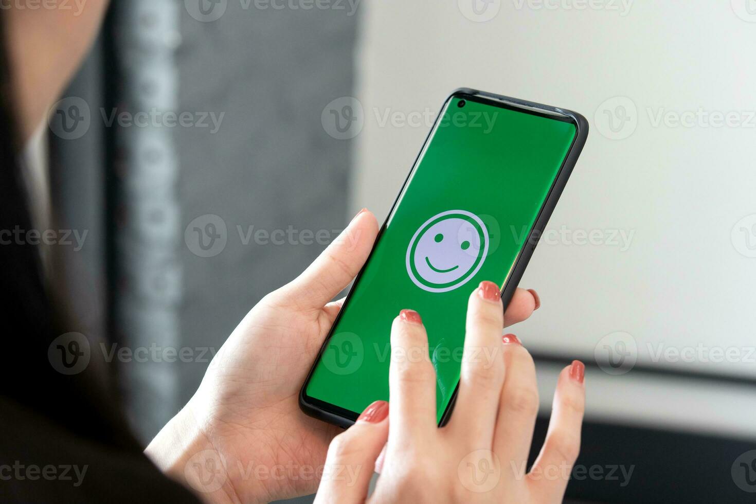 Woman holds a Smartphone with happy emoticons on the screen at a restaurant. concept of evaluating customer satisfaction at very good level of customer service photo