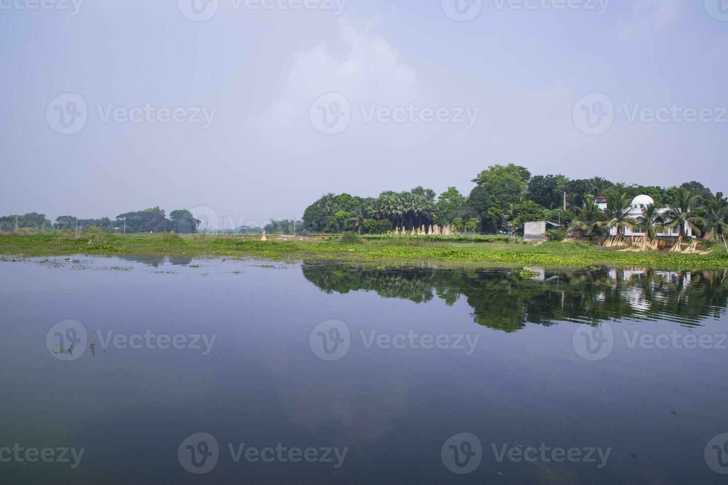 reflexión de arboles en el lago agua en contra el azul cielo paisaje campo en Bangladesh foto