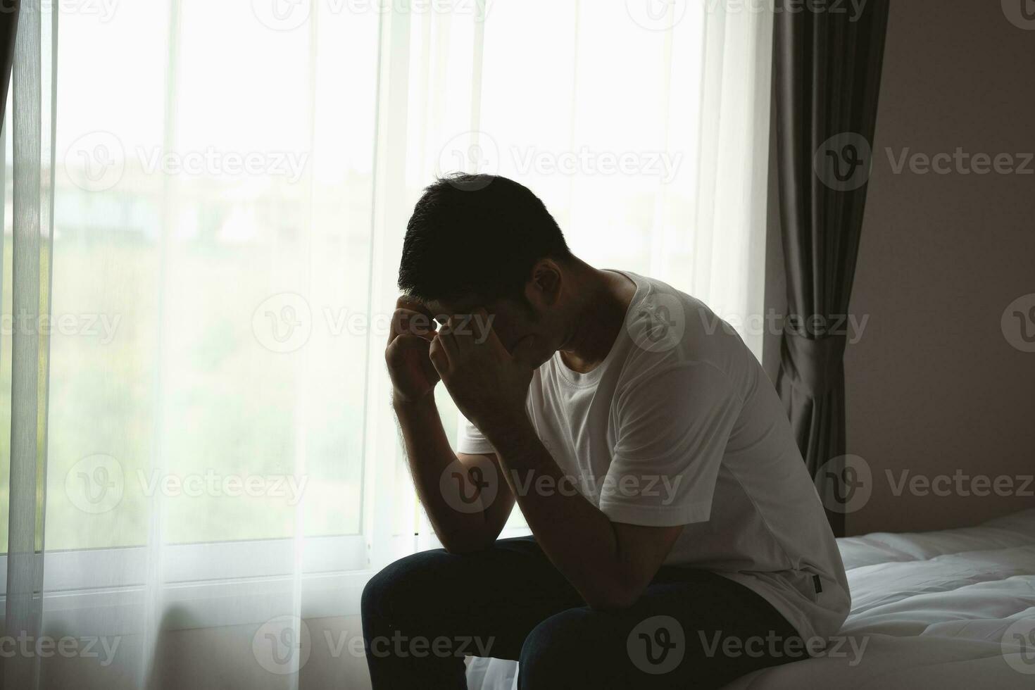 Silhouette depressed man sadly sitting on the bed in the bedroom. Sad asian men suffering depression insomnia awake and sit alone on the bed in bedroom. Depression health people concept. photo
