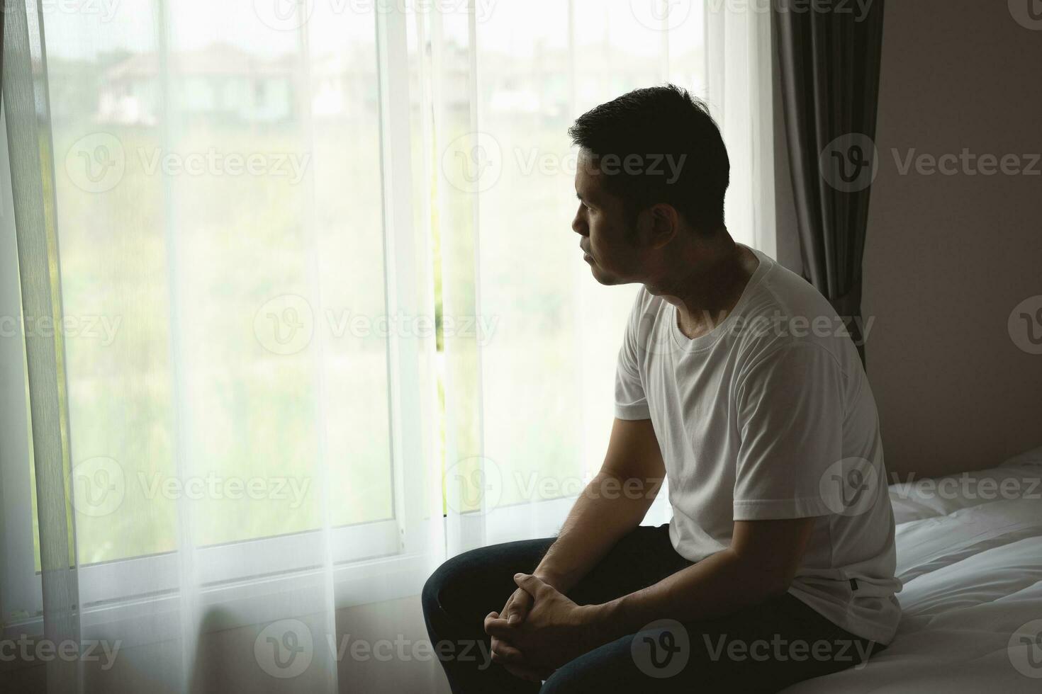 Silhouette depressed man sadly sitting on the bed in the bedroom. Sad asian men suffering depression insomnia awake and sit alone on the bed in bedroom. Depression health people concept. photo