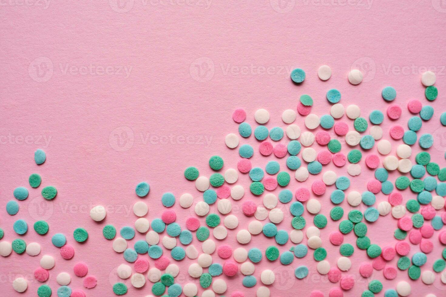 Multi-colored confectionery topping on a pink. photo