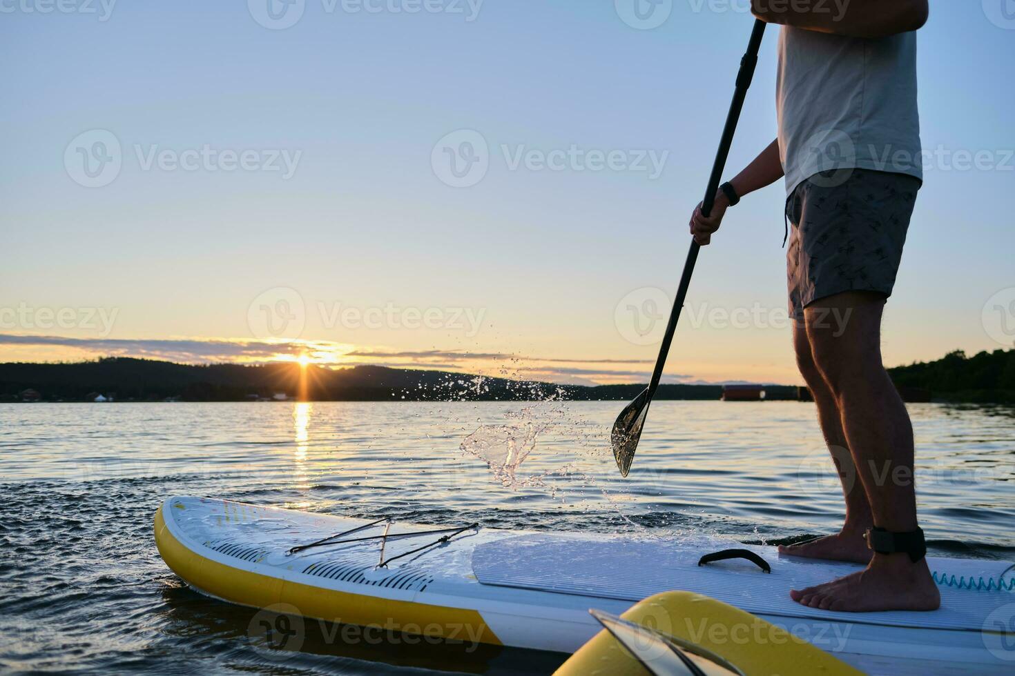 Male legs on a paddle board. photo