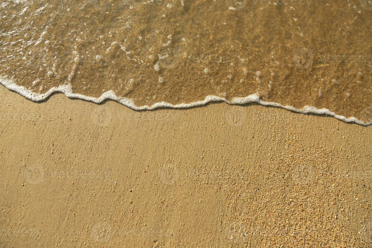 Close Up soft wave flow beautiful ocean on sandy beach. Background. sunshine in the evening. top view. photo
